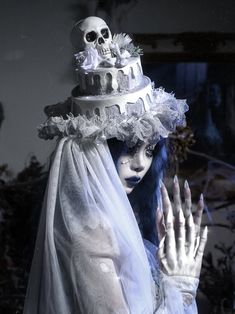 a woman with blue hair and makeup holding her hands up