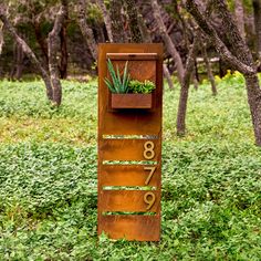 a metal planter with plants in it sitting on the side of a tree lined field