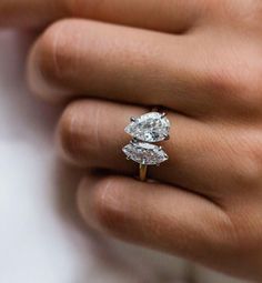 a woman's hand with a diamond ring on top of her finger and an engagement band