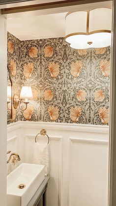 a white sink sitting under a bathroom mirror next to a wall mounted faucet