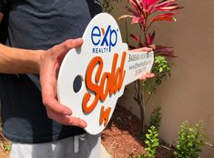 a man holding up a sign that says expo realty