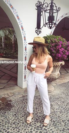 a woman standing in front of a building holding a cup