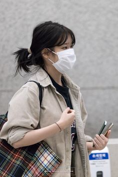 a woman wearing a face mask while holding her cell phone