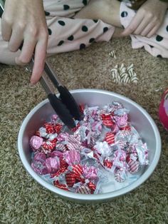 a person cutting up candy in a bowl on the floor with a pair of scissors