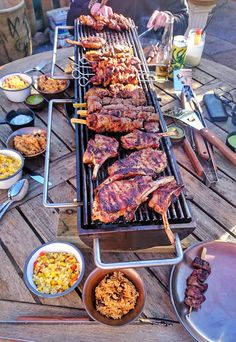 a table topped with lots of food and meat on top of it's grill