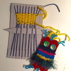 a piece of art made out of yarn and sticks with eyes on it, sitting next to an object that appears to be woven