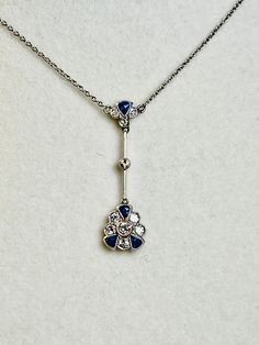 This gorgeous natural blue sapphire and diamond pendant lavaliere is a work of art. The pendant dates to the Edwardian period of the 1900's. The pendant features ten old cut diamonds and four blue sapphires set in clusters.  The pendant measures approximately 27 mm x 9 mm at the widest point. The two clusters are separated by a bar of gold with a single diamond at the center. The diamonds are bright and lively. The sapphires are a lovely deep blue. The pendant is stamped PLAT and 18CT -- the pen Edwardian Art, 18k Gold Necklace, Natural Blue Sapphire, Display Boxes, Diamond Pendant, Deep Blue, Antique Jewelry, Blue Sapphire, Sale Items