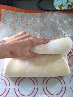 a person is kneading dough on top of a mat with a hand holding it