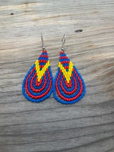 These blue and red earrings are set off perfectly with a vibrant yellow 'V" pattern. Hand crafted with care and attention to detail, these earrings are sure to make a statement wherever you go! Dangle Teardrop Earrings With Tiny Beads As Gift, Unique Handmade Teardrop Beaded Earrings, Gift Teardrop Dangle Earrings With Tiny Beads, Red Teardrop Jewelry With Tiny Beads, Gift Teardrop Earrings With Colorful Beads, Unique Handmade Multicolor Teardrop Earrings, Handmade Yellow Teardrop Earrings, Handmade Yellow Teardrop Earrings As A Gift, Handmade Teardrop Beads For Gifts