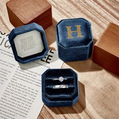 three wooden boxes with rings in them sitting on a table next to an open book