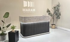 the reception desk is next to two potted plants and a sign that says marram design office