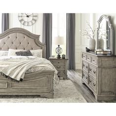 a bedroom with a bed, dresser and mirror on the wall in front of it