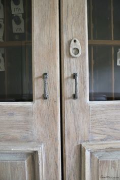 two wooden doors with glass inserts on each side and one has a keyhole in the middle