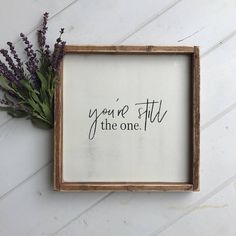 a framed sign with the words you're still the one next to some flowers