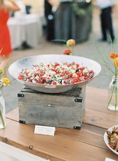 a table topped with lots of food and vases filled with flowers on top of it