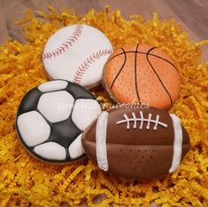 three decorated cookies in the shape of football, basketball and soccer ball on yellow flowers