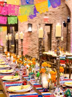 a long table is set with candles, plates and place settings for mexican themed dinner