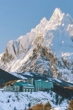 the mountains are covered with snow and there is a building in the foreground