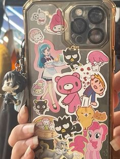 someone is holding up their phone case with many stickers on the front and back