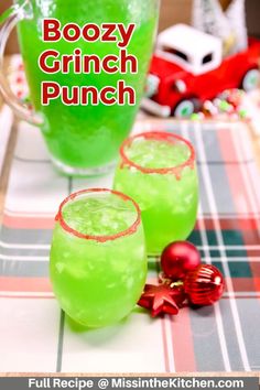 two glasses filled with boozy grin punch sitting on a plaid tablecloth next to a christmas ornament