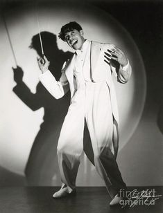 a man in a white suit holding an umbrella