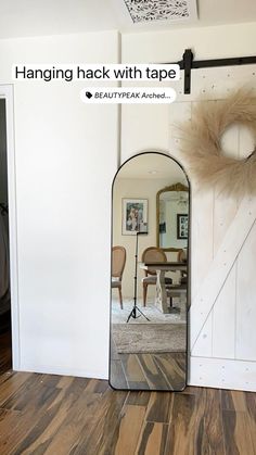 a mirror sitting on top of a hard wood floor next to a wall with a door