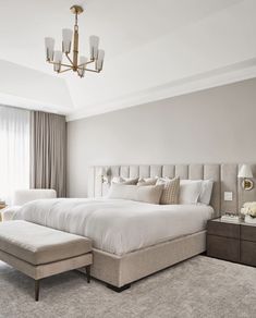 a large white bed sitting in a bedroom on top of a carpeted floor next to a window