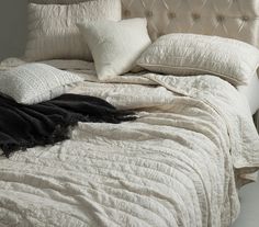 an unmade bed with white sheets and pillows