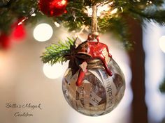 an ornament hanging from a christmas tree decorated with newspaper strips and red ornaments