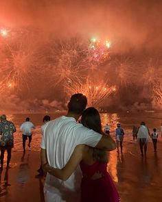 two people embracing each other in front of fireworks