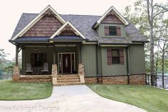 a green house with brown shingles and two story windows on the second floor is shown