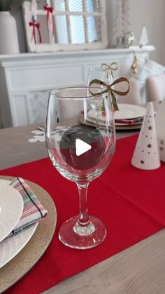 a table set for christmas with plates, napkins and wine glasses on top of it