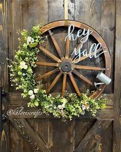 a wooden wheel with flowers and greenery on it that says hey sale next to a watering can