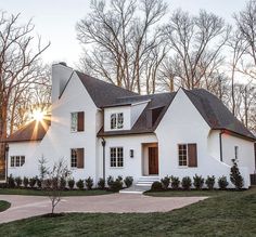 a white house with trees in the background and sun shining through the windows on one side