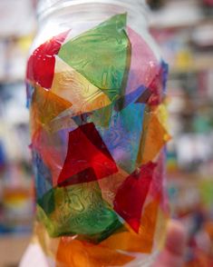 a jar filled with lots of different colored pieces of plastic wrapper sitting on top of a table