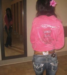 a girl in jeans and a pink shirt is looking at her reflection in the mirror