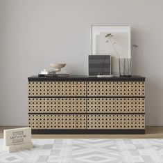 a black and white dresser sitting on top of a wooden floor next to a wall