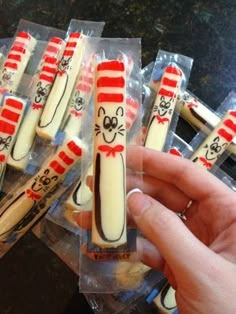 a person holding some kind of cat in the hat shaped cookies with candy sticks sticking out of them