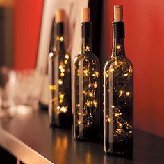 three bottles with lights in them sitting on a table