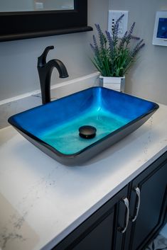 a bathroom sink that has a blue glass bowl on top of it with a black faucet