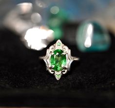 Gorgeous LARGE Green Tsavorite Garnets set in a stunning art deco style setting. This ring has all that glam and drama with the vibrant greens glowing off the high polished silver. There are two small Tsavorite Garnets that sit top and bottom of this ring. If you love rings with drama and color then this is definitely for you, the emerald greens from the natural Tsavorite will spark inspiration and pure joy. Its an all around BOMBSHELL of a ring.This ring is set in a size 8.Tsavorite Garnet: Cla Collectible Green Emerald Ring With Center Stone, Art Deco Emerald Ring As Gift, Green Jewelry With Accent Stones For Collectors, Collectible Green Jewelry With Accent Stones, Green Collectible Jewelry With Accent Stones, Art Deco Emerald Ring For May Birthstone, Wedding White Gold Tsavorite Jewelry, White Gold Jewelry With Tsavorite And Accent Stones, Art Deco Silver Emerald Ring