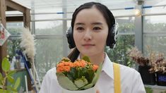 a woman wearing headphones holding a bouquet of flowers