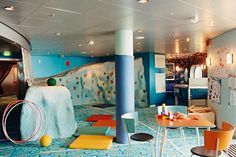 an indoor climbing wall in the middle of a room with chairs, tables and rugs