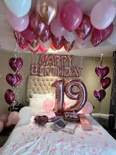 a bed topped with lots of balloons next to a number 19 sign and some books