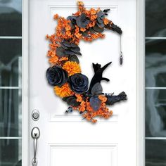 a white door with a black cat and orange flowers on the front, surrounded by leaves