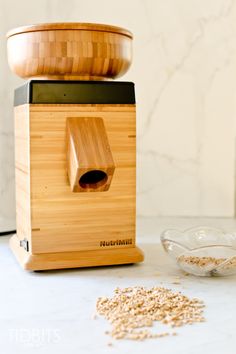 a wooden blender sitting on top of a counter next to a bowl filled with oats