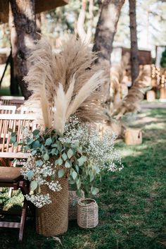 two vases filled with flowers sitting on top of a grass covered field next to wooden chairs