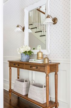 a wooden table with baskets on it and a large mirror above the table in front of it