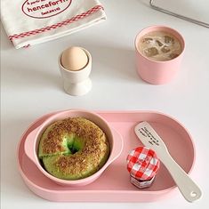 a pink tray topped with a donut next to a cup of coffee and an egg