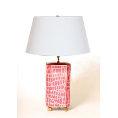 a pink lamp with a white shade on it's side and a gold base